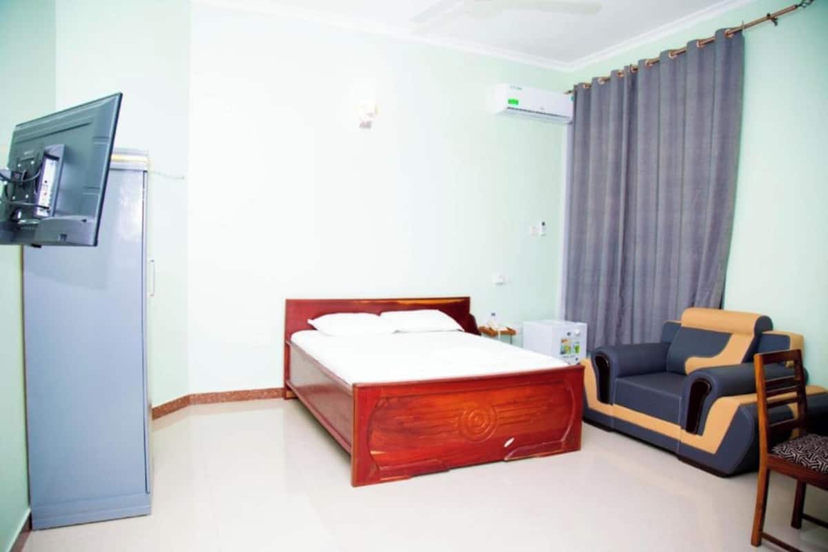 A bedroom with a wooden bed, a sofa, a TV, and a desk.