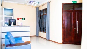 Zona de recepción con escritorio, computadora y un sofá azul.