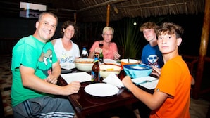 Un grupo de personas sentadas alrededor de una mesa con comida y bebidas.