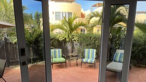 A patio area with two chairs and a table, a wooden fence, and a building in the background. - 1A Casa Un Amor, Cerritos Beach Condo (El Pescadero)