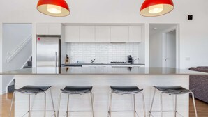 A modern kitchen with a central island, stainless steel appliances, and a seating area with bar stools.