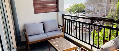 A balcony with a wooden sofa, a small table, and a chair.