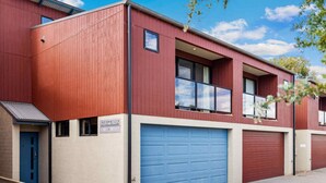 A red building with a blue garage door, a small window, and a sign that reads "STOCKYARDS". - Stockyards 1 with uninterrupted mountain and lake views (Jindabyne)