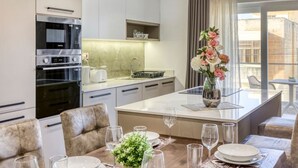 A modern kitchen with built-in appliances, a dining area with a central island, and a view of the city through large windows. - Luxurious, spacious fully equipped home in Swieqi (Is-Swieqi)