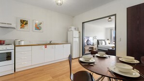 A modern kitchen with white cabinets, a wooden countertop, and a dining area with a table set for four.