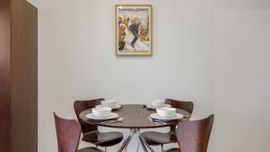 A dining area with a round table, four chairs, and a poster on the wall.