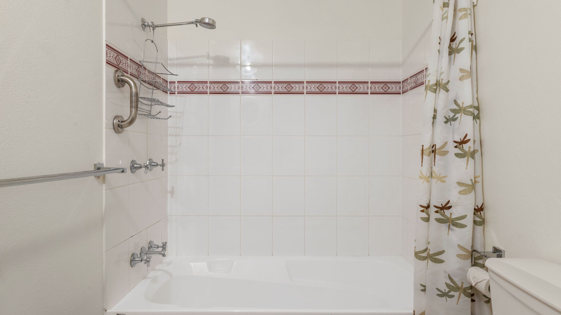 Et badeværelse med badekar, bruser og toilet.