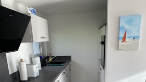 Una cucina moderna con mobili bianchi, un piano di lavoro nero e un pavimento in legno.