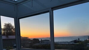 Camera da letto con un letto grande, un lucernario e vista sul tramonto sul mare.