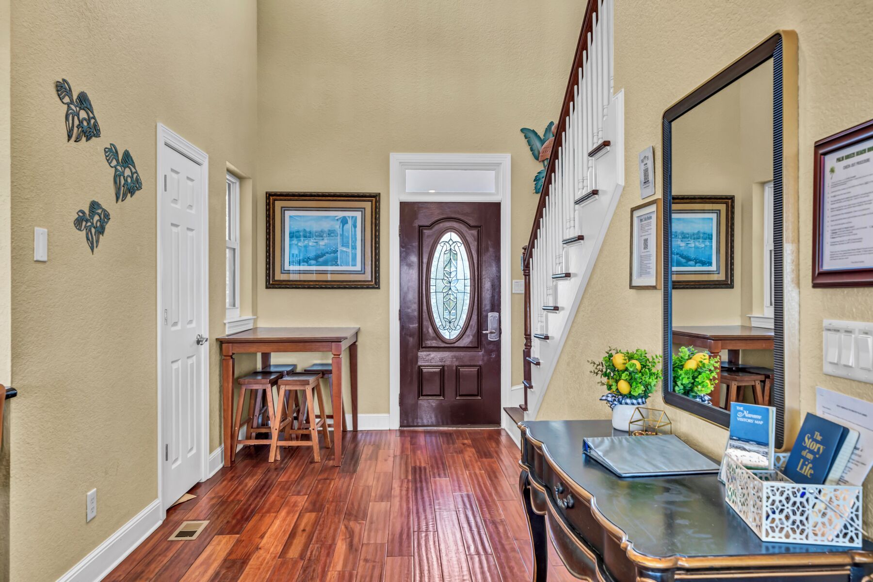A hallway with wooden flooring, a dark wooden door, and a staircase with white railings.