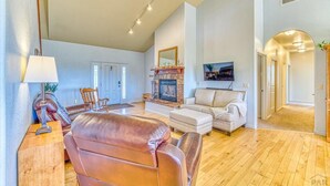 A spacious living room with a fireplace, leather sofa, and a television.