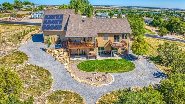 A large house with a spacious driveway, a covered patio, and a solar panel on the roof.