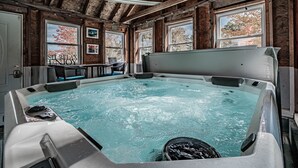 Ein Whirlpool in einer rustikalen Holzhütte mit Holzbalken, einem Tisch mit Stühlen und einem Schild mit der Aufschrift 'SIT RELAX ENJOY'.