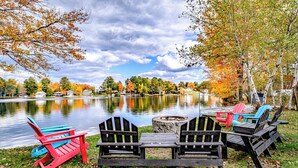 Sitzbereich am Seeufer mit Adirondack-Stühlen und einer Feuerstelle.