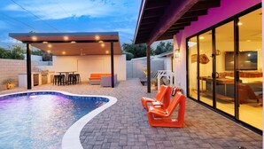 A modern outdoor pool area with a covered seating area, lounge chairs, and a patio with a brick floor. - Steps to Old Town*Scottsdale Haven*Heated Pool*Spa* (Scottsdale)