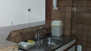 A small kitchen with a sink, a faucet, a trash bin, and a cabinet. - Ap Banho de Mar (Ondina Salvador)