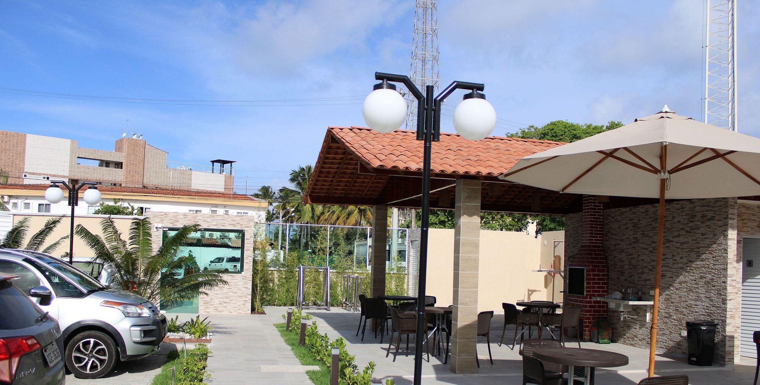An outdoor patio area with tables and chairs, a brick wall, and a parked car.