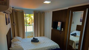 A bedroom with a bed, a TV, and a sliding door to a balcony.