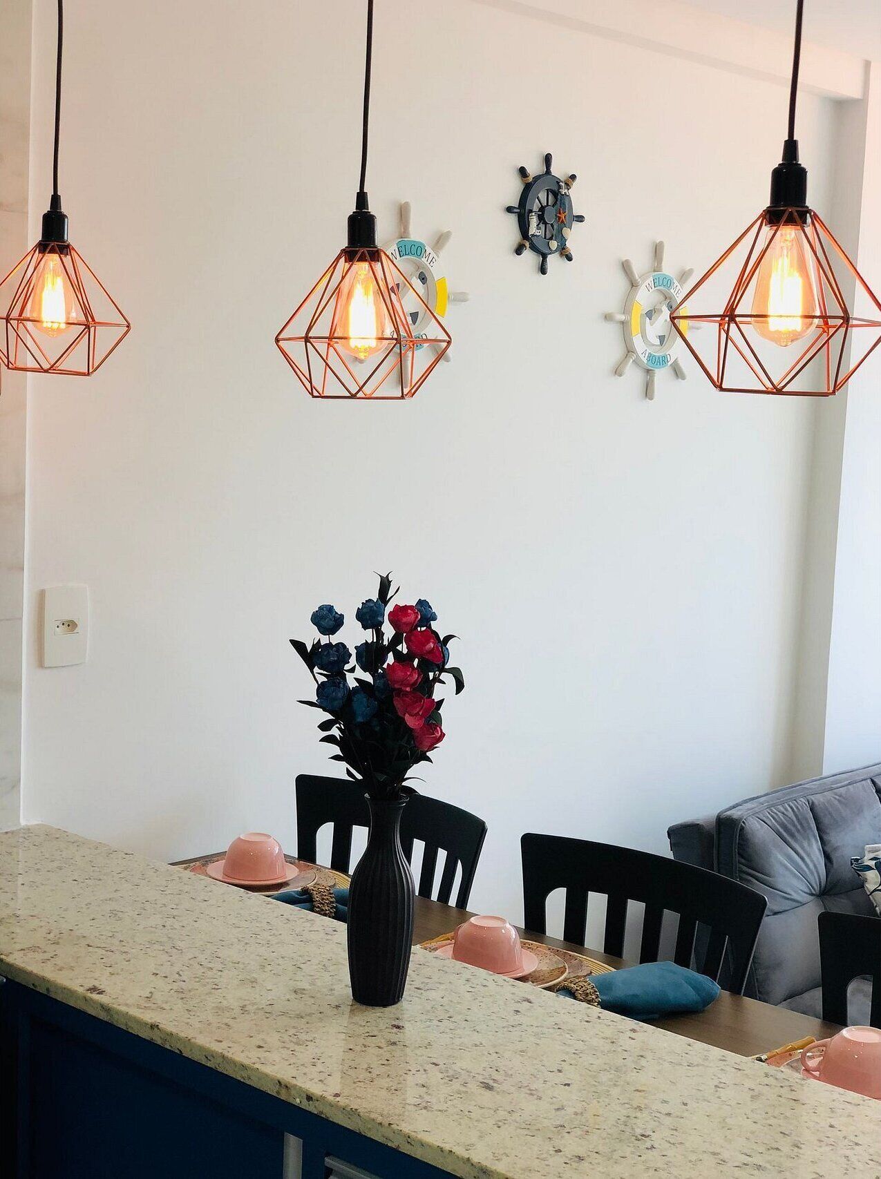 A modern kitchen with a central island, pendant lights, and decorative wall clocks.