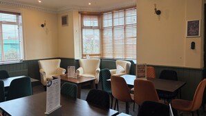 A restaurant with a corner seating area, multiple tables, and chairs. - Captain Howey Hotel (New Romney)