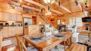 Interior de una cabaña de madera con comedor, cocina y sala de estar.