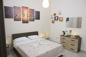 Un dormitori ben organitzat amb un llit, taules de nit, una petarrera i decoració mural.