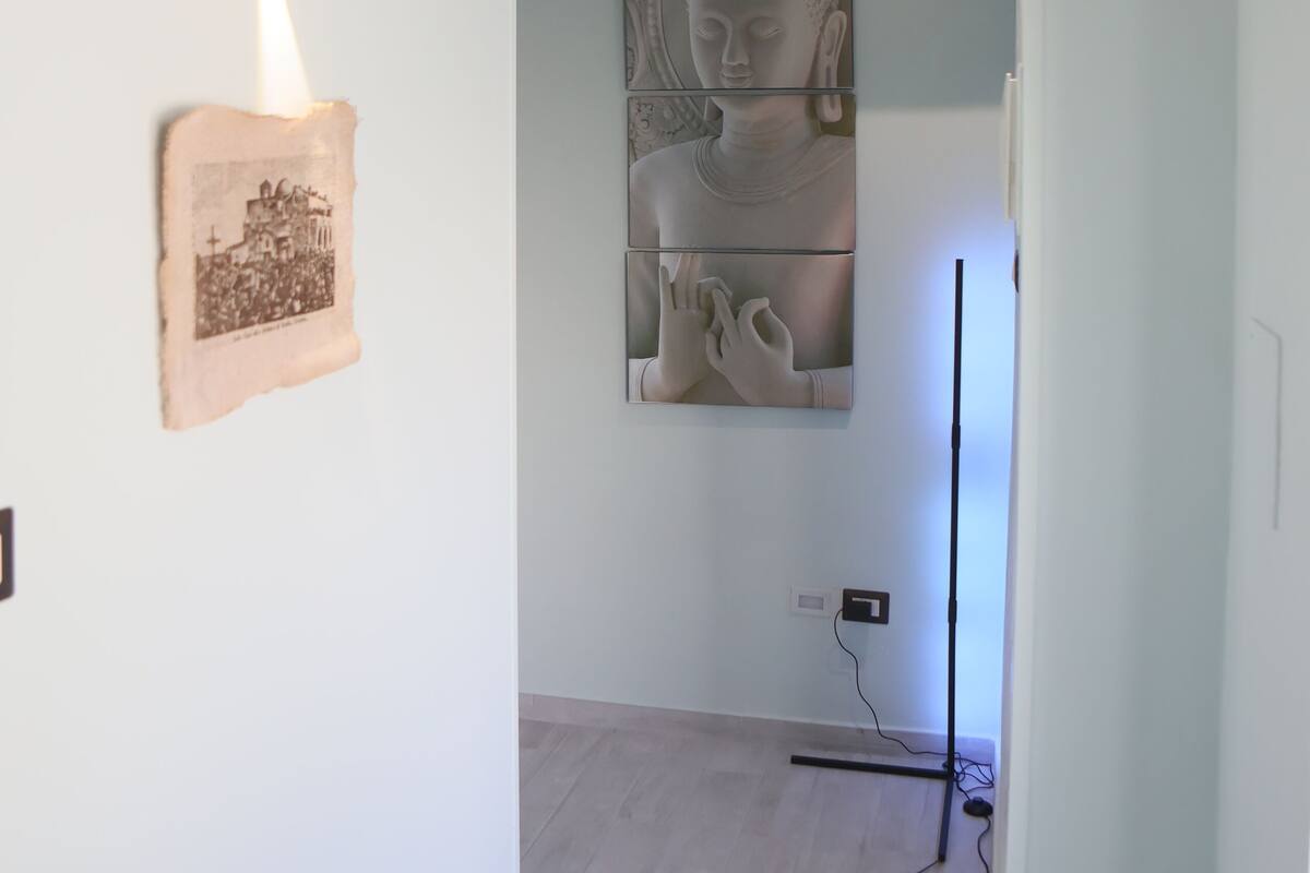Um corredor com luminária, quadro emoldurado e estátua de Buda.