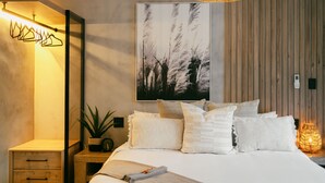 Un dormitorio con cama, mesita de noche, lámpara y espejo en la pared.