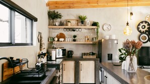 Una cocina moderna con armarios de madera, estufa integrada y encimera con diversos utensilios de cocina y plantas.