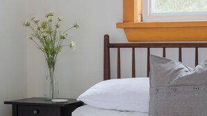 A neatly made bed with white bedding, a gray striped pillow, and a small vase with white flowers on a bedside table. - Doma Lodge - Cozy Muskoka Cabin in the Woods (Huntsville)