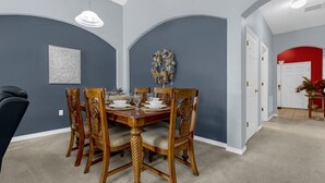A dining area with a round table set for six, surrounded by wooden chairs with intricate carvings. - Home in Davenport close to Parks w/Pool (Davenport)