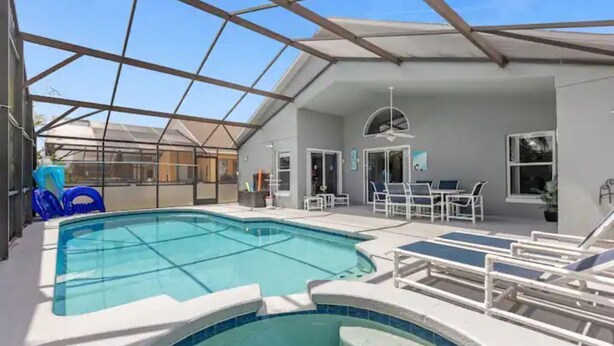 A pool area with a glass ceiling, lounge chairs, and a seating area. - Home in Davenport close to Parks w/Pool (Davenport)