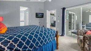 A bedroom with a bed, a television, and a sliding glass door leading to a balcony. - Home in Davenport close to Parks w/Pool (Davenport)