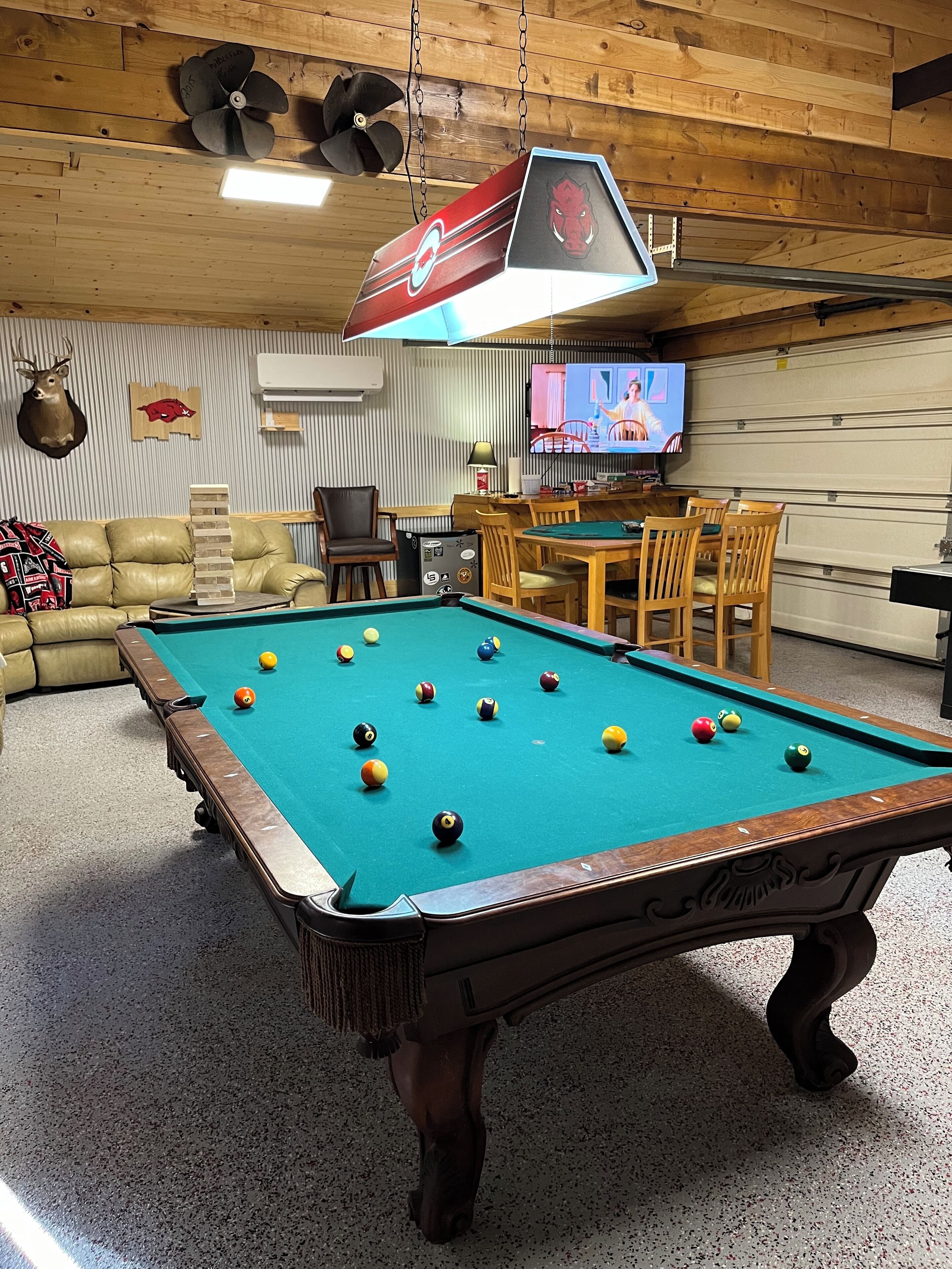 Una mesa de billar con bolas, un televisor y un techo de madera.