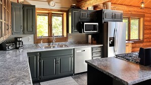 Una cocina moderna con encimeras de granito, electrodomésticos de acero inoxidable y armarios de madera.
