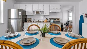 Une cuisine moderne avec des meubles blancs, un réfrigérateur en acier inoxydable, un four à micro-ondes et une cuisinière.