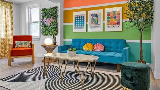 Un salon chaleureux et accueillant, avec un canapé bleu, un fauteuil rouge et une table basse ronde.