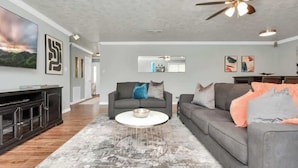 Ein modernes Wohnzimmer mit grauem Sofa, rundem Couchtisch und Deckenventilator.