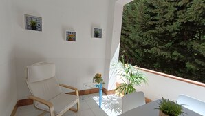 Un balcón con una silla, una mesa y plantas en macetas.