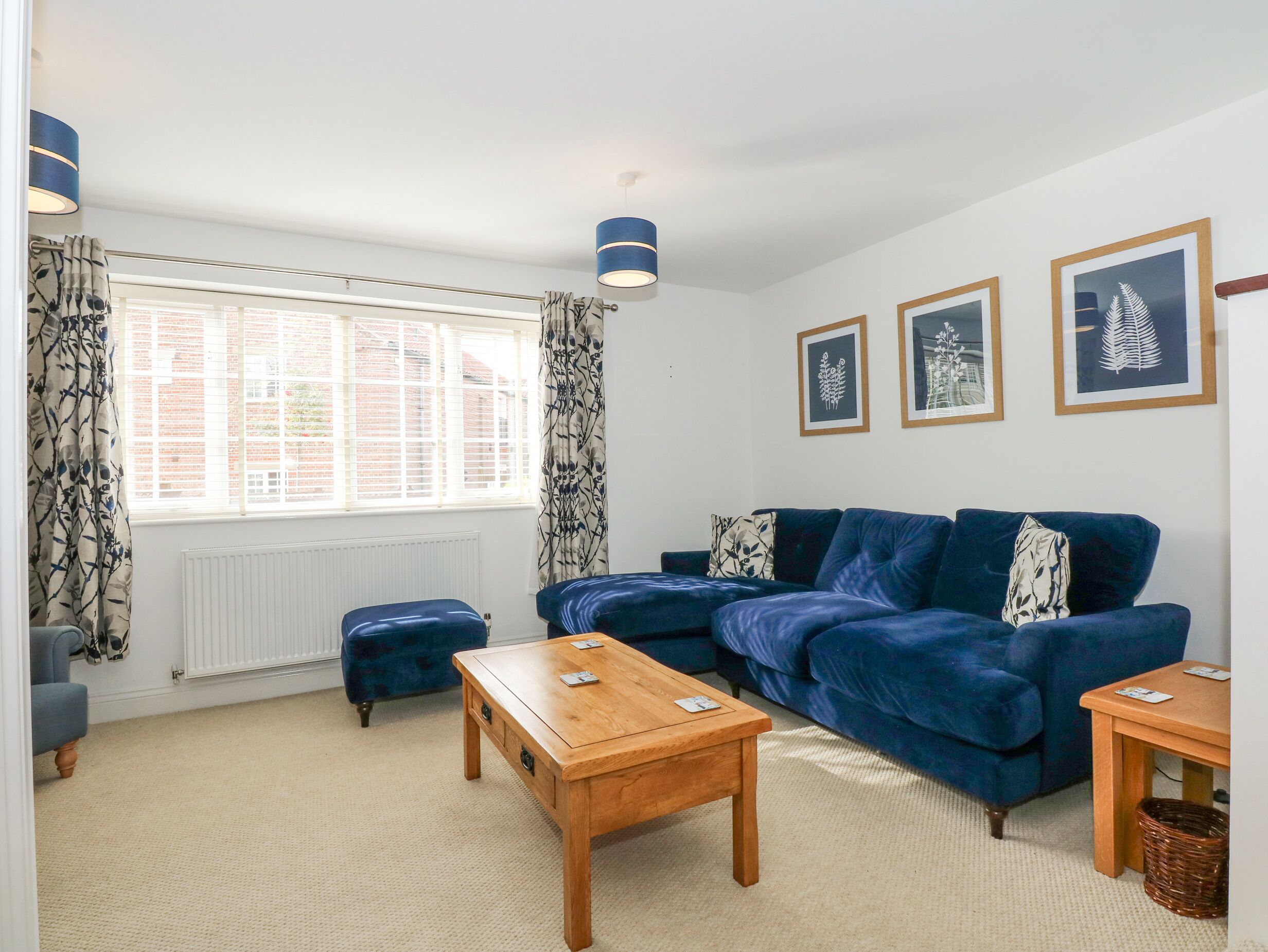 A living room with a blue sofa, a wooden coffee table, and a patterned curtain.