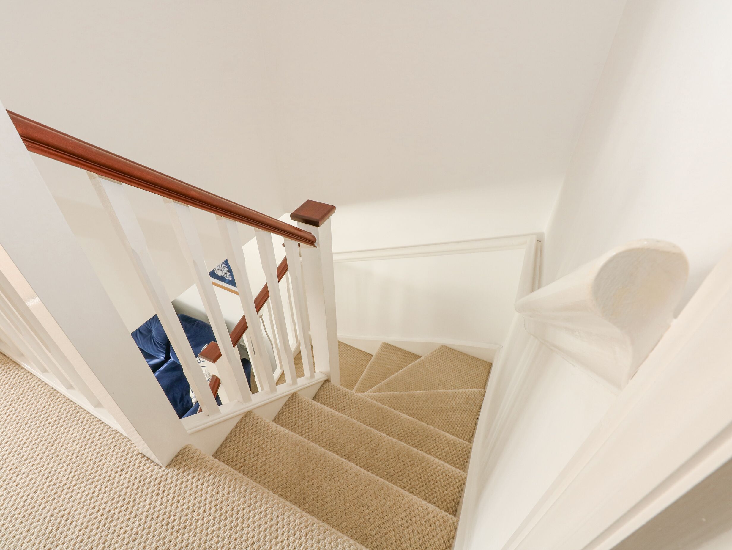 A staircase with a wooden handrail and beige carpeted steps.