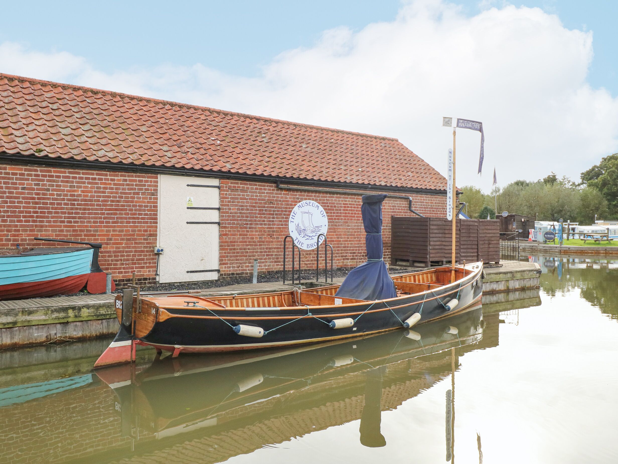 A rowboat docked at a canal with a brick building in the background.