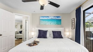 A bedroom with a bed, a ceiling fan, a window with curtains, and a painting of a beach. - Little Treasure House minutes from Beach & Mercato (Naples)