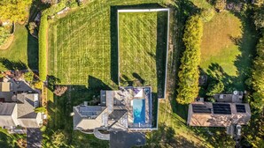 Luchtbeeld van een woonhuis met zwembad, zonnepanelen en een groot gazon.