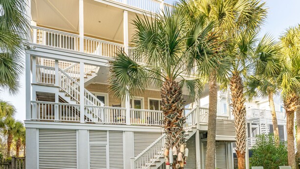 A pool area with a two-story building, palm trees, and a barbecue grill. - Beautiful Traditional Home with Private Pool! 5 BR 4 BA (Isle of Palms)