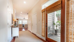 A hallway with a patterned rug, white doors, and a view of a patio with outdoor furniture. - Beautiful Traditional Home with Private Pool! 5 BR 4 BA (Isle of Palms)