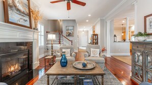 A spacious living room with a fireplace, a coffee table with decorative items, and a view into the dining area. - Beautiful Traditional Home with Private Pool! 5 BR 4 BA (Isle of Palms)