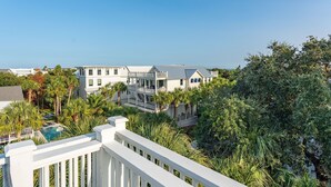 A large, multi-story building with a swimming pool, surrounded by lush greenery and palm trees. - Beautiful Traditional Home with Private Pool! 5 BR 4 BA (Isle of Palms)