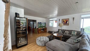Ein geräumiges Wohnzimmer mit grauem Sofa, einer Glastruhe und Holzboden.