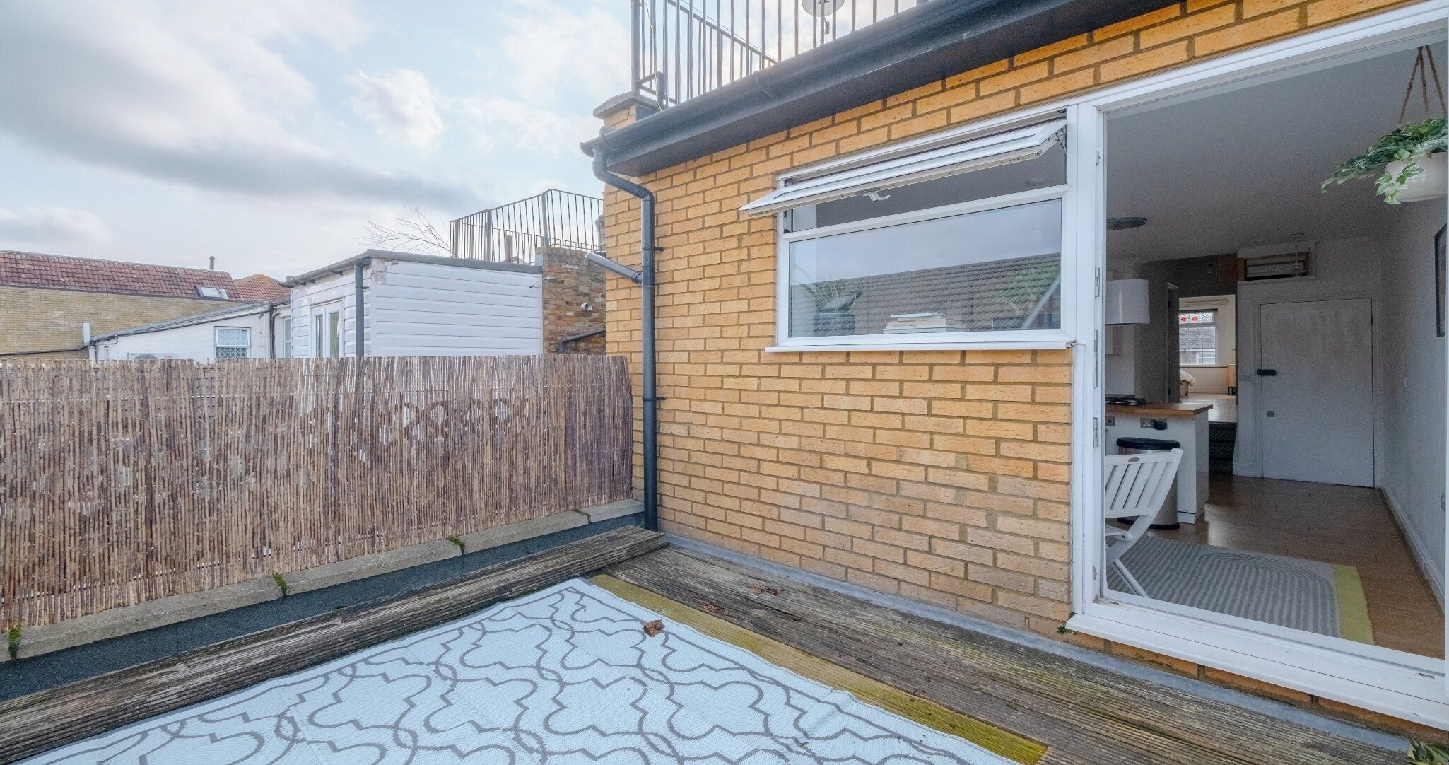 A residential property with a brick exterior, a wooden fence, and a small patio area.
